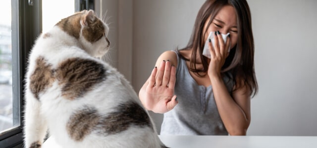 Frau zeigt Katzen Allergie Symptome